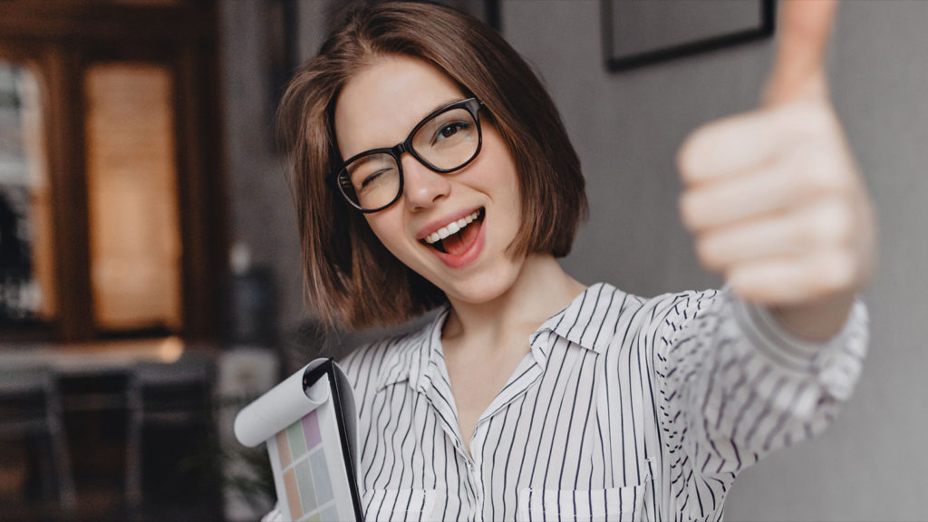 Farmacéutica sonríe a cámara sosteniendo un porta documentos